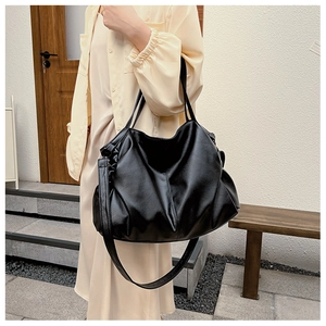 Detail of soft leather texture and stylish side drawstring on large black hobo tote bag