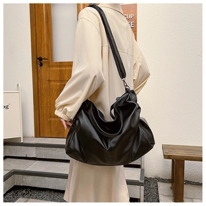 Close-up of a large black faux leather tote bag with lychee texture and wide strap