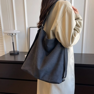 Minimalist large black canvas tote bag with wide strap shown on model in modern setting