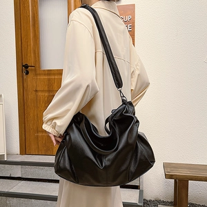 Large black leather hobo shoulder bag shown on model for stylish summer commuting outfits