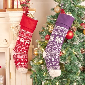 Knitted Christmas stocking set with reindeer patterns hanging on festive fireplace mantel