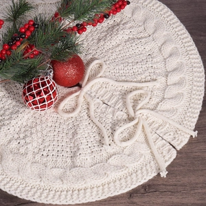 Detail of cable knit Christmas tree skirt in off-white with festive decorations