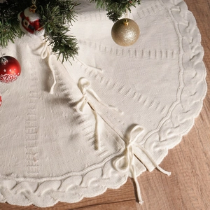 Falda de árbol de Navidad de punto blanco crema con borde trenzado sobre fondo de madera