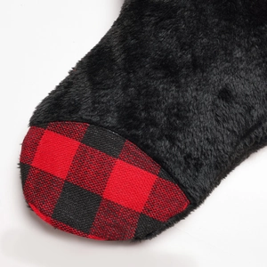 Detailed close-up of soft black faux fur and red buffalo plaid fabric on a holiday sock