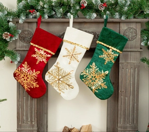 Three velvet Christmas stockings with gold snowflake embroidery on a fireplace mantel