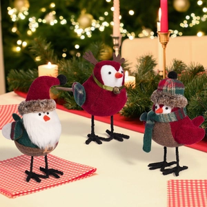 Three Christmas bird figurines in Santa, reindeer, and winter outfits on a festive table