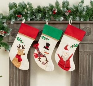 Three hanging Christmas stockings featuring reindeer, snowman, and Santa motifs on a mantel