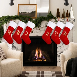 Set of six red velvet Christmas stockings with golden letters on a marble fireplace