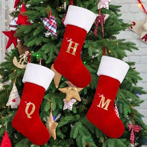 Three red velvet Christmas stockings with white fur and gold glitter letters H, Q, and M
