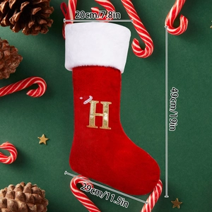 Detail of red Christmas stocking with golden glitter letter H and plush white faux fur trim