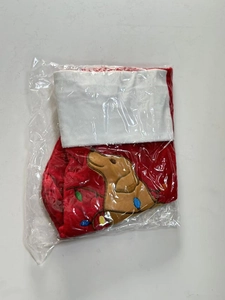 Detail of red Christmas stocking with brown dog embroidery in clear plastic packaging