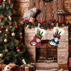 Dog bone shaped Christmas stockings with plaid pattern and paw prints on fireplace mantle