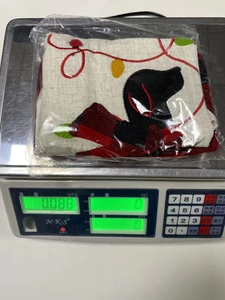 Detail von bestickten Weihnachtssocken mit Hundemotiv auf einer Waage bei 0,088kg Gewicht