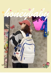 Close-up of white minimalist backpack with blue zipper trim and panda plush charm