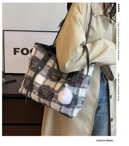 Detail of grey plaid canvas tote bag with fringed edges and plush pompom charm