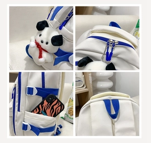 Detail view of white backpack with blue accents featuring side pocket and plush charm