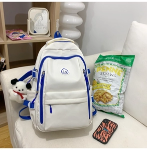Close-up of a large white nylon backpack with blue contrast zippers and plush dog charm