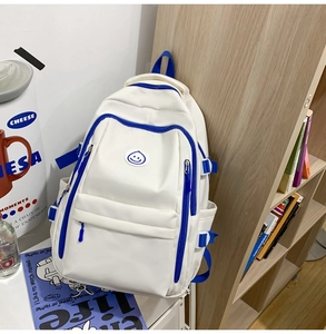 Detail of a white and blue contrast backpack with a smiley face icon and side straps