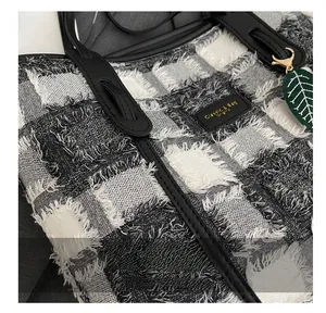 Detailed view of tweed canvas tote featuring fringe edges and golden hardware accents