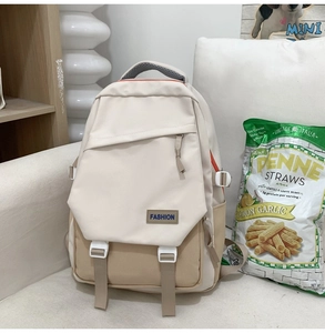 Détail d'un sac à dos patchwork beige et kaki avec logo FASHION sur un canapé blanc