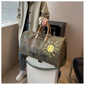 Detail of army green canvas travel bag with playful hand-drawn graffiti and leather handles