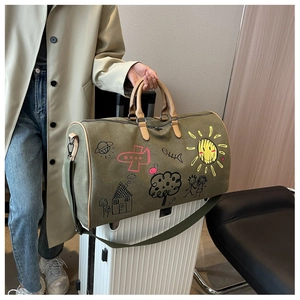 Macro detail of olive green canvas travel bag with playful colorful cartoon doodles