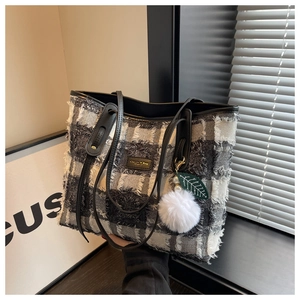 Close-up of black and white checkered tweed tote bag with fringe edge and leather handles