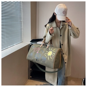 Detail of army green canvas travel bag with colorful graffiti and leather handles