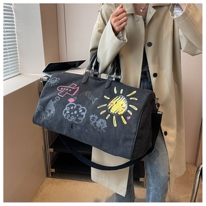 Detail of black canvas travel bag with colorful hand-drawn graffiti art and leather handles