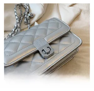 Detail of silver quilted handbag featuring a metallic twist-lock and woven chain strap