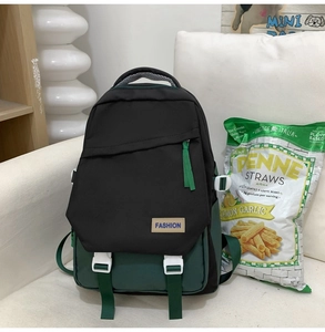 Détail d'un sac à dos bicolore noir et vert grande capacité sur un canapé blanc