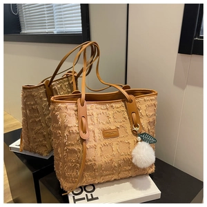 Detail of caramel canvas tote with fringe texture and plush ball charm accessory