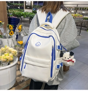 Detail of a large beige backpack with blue accents and a plush dog charm in a shop