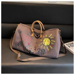 Detail of canvas travel bag with colorful doodle patterns and leather handles on a sofa