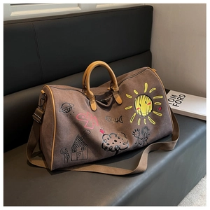 Detail of canvas travel bag featuring colorful doodle prints and leather handles