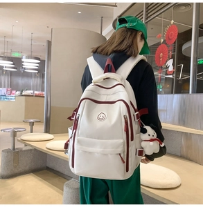 Close-up of white waterproof nylon backpack with red zipper accents and cute plush charm