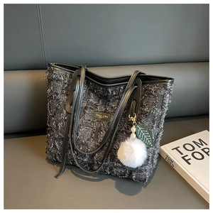 Close-up of grey tweed tote bag with fringe detail, leather handles and pearl fur charm