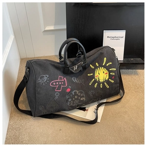 Detail of large black canvas travel bag with artistic hand-drawn graffiti patterns