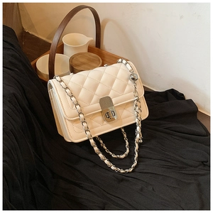Detail of quilted leather crossbody bag in creamy white with silver chain strap and lock