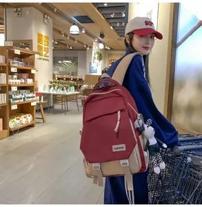 Détail du sac à dos en toile bordeaux et beige avec un pendentif chien sur un modèle