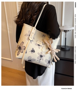 Détail du sac cabas en toile blanc cassé avec imprimés floraux et breloque lapin