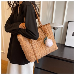 Detail of canvas tote bag featuring textured fringe patterns and brown leather handle