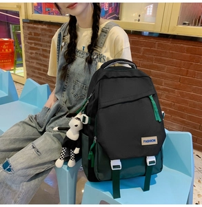 Détail d'un sac à dos style collège avec rabat vert, boucles blanches et peluche