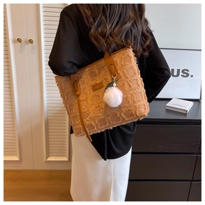 Detail of brown textured tote bag with square frayed patterns and cute pompom charm