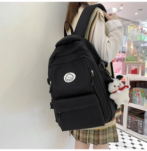 Detail view of large capacity black school backpack with multiple zippers and plush dog charm