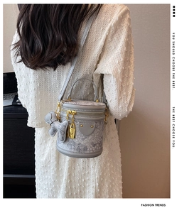Detail of grey barrel crossbody bag with marble pattern, gold hardware and bear charm
