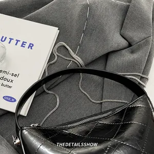 Detail of black quilted leather bucket bag with smooth handle and metal chain strap