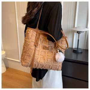 Detail of canvas tote bag with textured grid patterns and brown leather strap detail