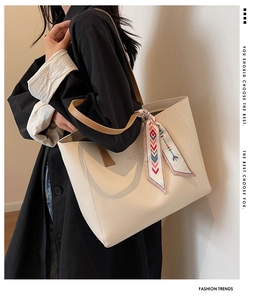 Detail of cream tote bag with ethnic scarf decor and gold Fashion trend lettering