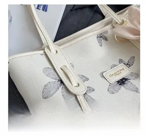 Gros plan d'un sac cabas en toile crème avec motif floral et poignées en cuir chic